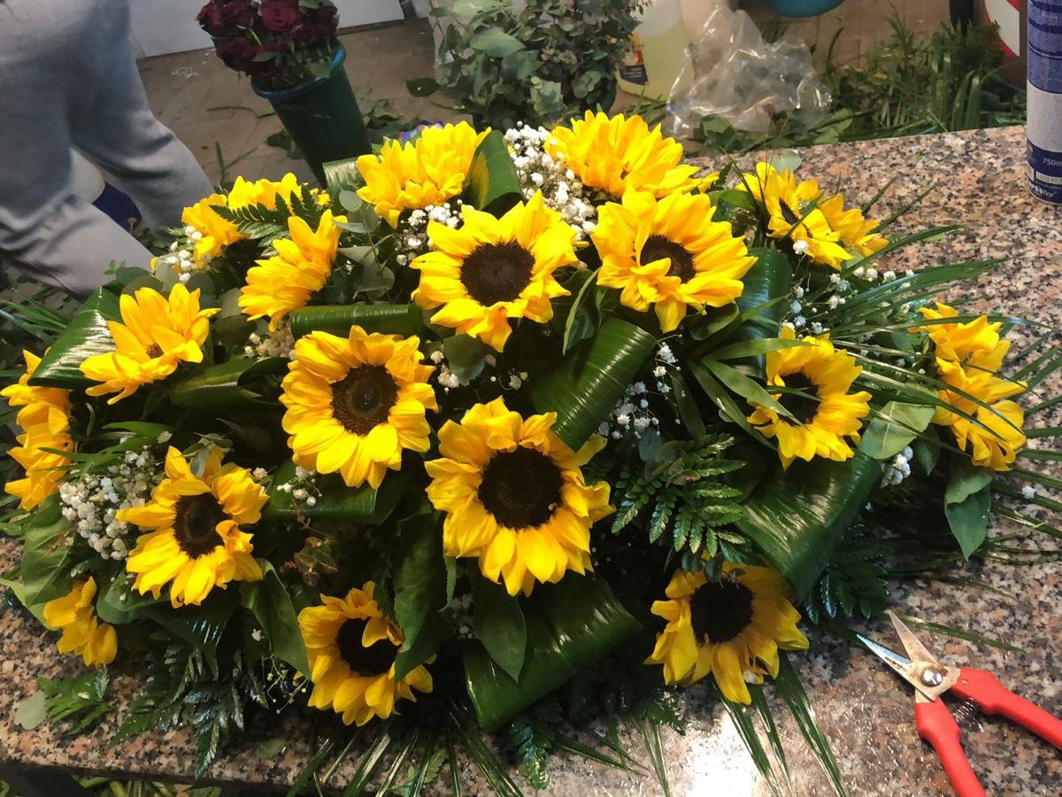 Composizione funebre con girasoli in lavorazione nel laboratorio dell'agenzia